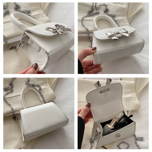 Close-up of a white mini handbag with silver bow detail and delicate metal chain strap