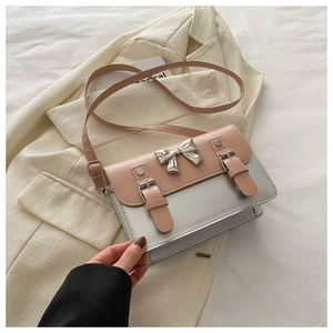 Detailed view of pink and silver crossbody bag with metal bow and buckle straps