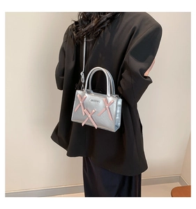 Sac à bandoulière argenté avec nœuds roses et logo en métal sur blazer noir