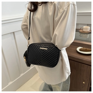 Detail of black chevron quilted crossbody bag with gold metal trim and mini pouch