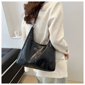 Glossy black hobo bag shown on shoulder, highlighting the retro faux leather texture