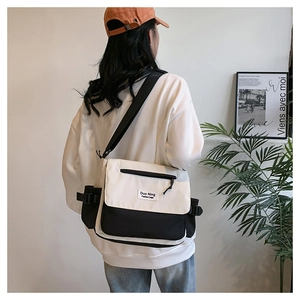 Detailed view of large canvas messenger bag with contrast stitching and side buckle detail