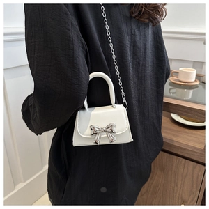 Detailed back view of a white fashion crossbody bag with silver bow accent and metal chain