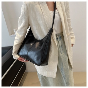 Detailed view of the shiny black leather tote bag with vertical stitching and smooth texture