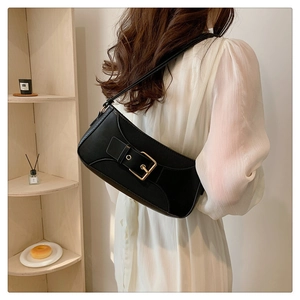 Detail of minimalist black leather baguette bag with a bold gold decorative buckle