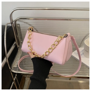 Detail of a pink cylindrical handbag with thick gold chain handle and leather strap