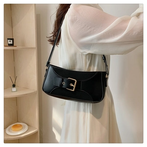 Detailed side view of a black leather underarm bag featuring a large metal buckle on the shoulder