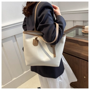 Detail view of the white and brown contrast leather tote bag showing the fashion logo