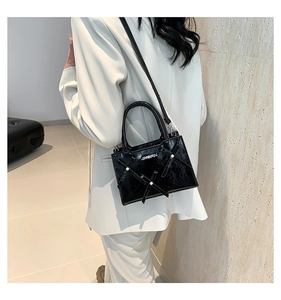Détail du sac bandoulière en cuir verni noir avec accents de perles et logo en métal