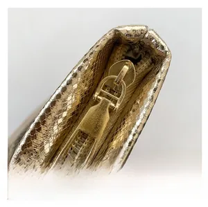 Detail of gold snake-embossed vanity bag with premium light gold metal zipper
