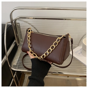 Close-up of smooth dark brown leather bag with chunky gold chain handle and strap