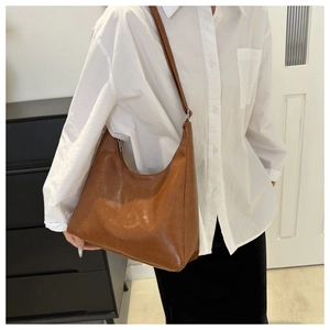 Detail view of a vintage brown leather tote bag with a crescent shape and silver zipper