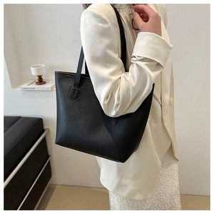 Elegant black large leather tote bag shown on model in a minimalist modern interior setting
