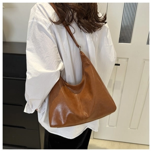 Brown vintage leather hobo bag worn crossbody style over a white shirt for commuting