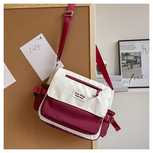 Detail of color-block canvas messenger bag with brand label and adjustable buckle