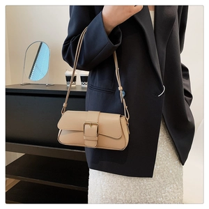 Detail view of stylish beige faux leather shoulder bag with elegant golden metal buckle