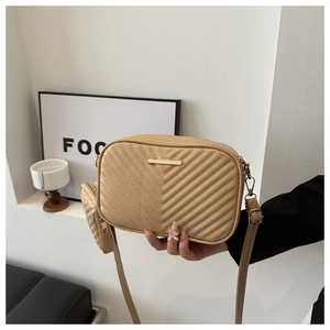 Detail of beige quilted square crossbody bag featuring a mini pouch and gold hardware