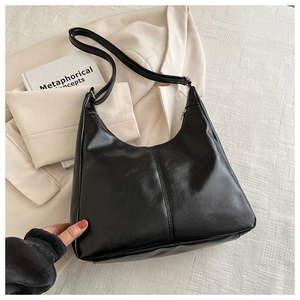 Detail view of a black faux leather hobo shoulder bag with a zipper and central seam