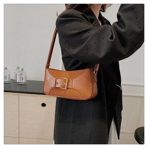 Detail of a brown leather shoulder bag with a stylish oversized decorative buckle