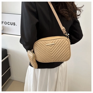 Detail of light khaki quilted crossbody bag with gold hardware and side coin pouch accessory