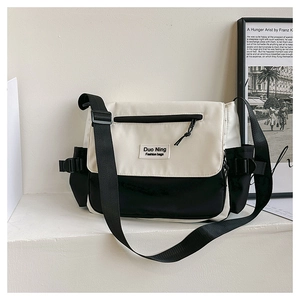 Detail of minimalist black and white canvas messenger bag with Duo Ning brand patch