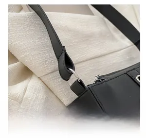 Détail d'un sac porté épaule en cuir noir mat avec anneaux argentés et coutures précises