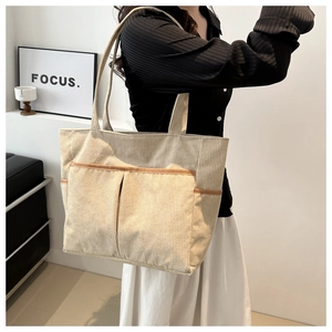 Detailed view of the large corduroy tote bag with front pocket shown on a model