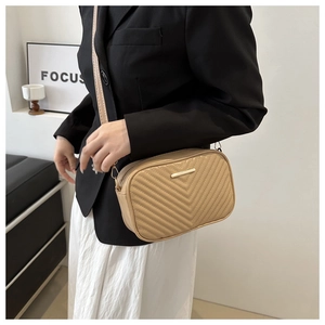 Detailed view of beige PU leather square bag with V-quilted texture and gold hardware