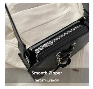Détail d'une fermeture éclair argentée sur un sac à main noir avec lacets décoratifs
