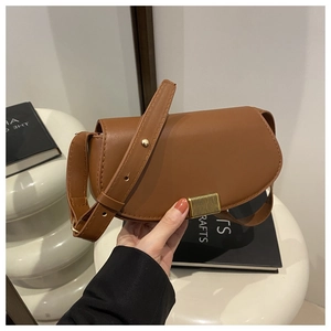 Detailed view of brown leather saddle bag with vintage gold clasp and textured finish
