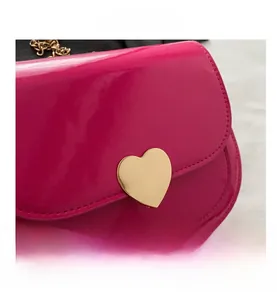 Detail der Lackledertasche mit großer goldener Herzschnalle und elegantem Kettenriemen