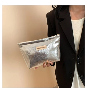 Detail of silver metallic makeup bag featuring a leather patch and secure metal zipper