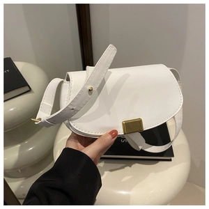 Detailed view of white leather saddle bag with rectangular gold metallic buckle and wide strap