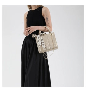 Detailaufnahme der goldenen gesteppten Handtasche mit Seidenschal und Metallkette