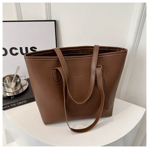Detail of large brown tote bag with FASHION & BAG embossing on smooth leather texture