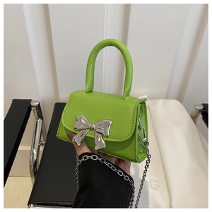 Detail of neon green mini bag with silver mirror bow buckle and metal chain strap