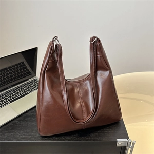 Brown vintage large capacity tote bag and laptop on a black desk for office commuting