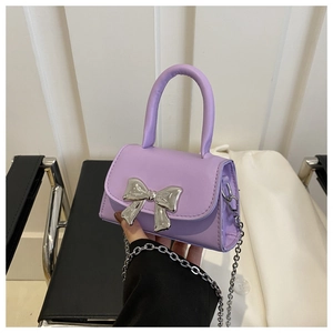 Detail of a purple PU square bag featuring a silver metal bow and fine chain strap