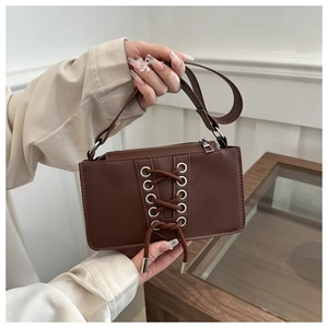 Détail du sac à bandoulière marron avec design à lacets et œillets en métal argenté