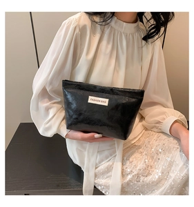Detail of black embossed leather pouch with a white Fashion Bag label held by a model