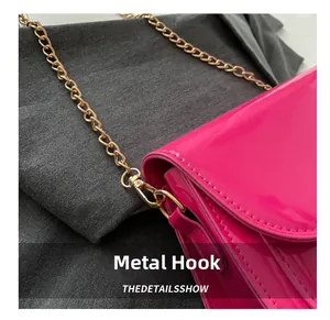 Detail einer pinken Lackleder-Handtasche mit polierter goldener Metallkette und Haken
