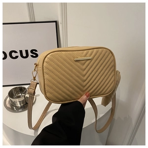Close-up of beige crossbody bag with V-shaped chevron quilting and gold metal detail