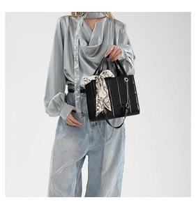 Details der schwarzen gesteppten Handtasche mit Seidenschal und goldener Kette