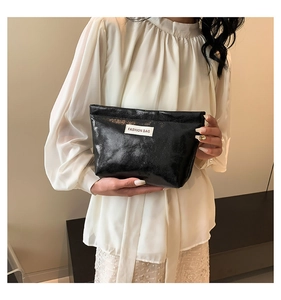 Detail of black textured faux leather handbag with white woven Fashion Bag label