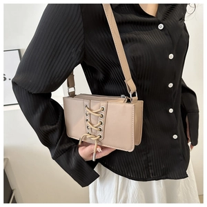 Détail d'un sac bandoulière beige avec laçage élégant porté par un mannequin chic