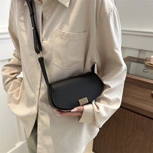 Retro black semi-circle saddle bag with gold buckle on crossbody strap shown on model