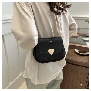 Details der glänzenden schwarzen Lackleder-Schultertasche mit goldener Herz-Metallschnalle