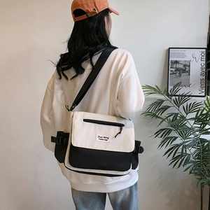Classic black and white canvas messenger bag shown on model from a 45-degree back angle