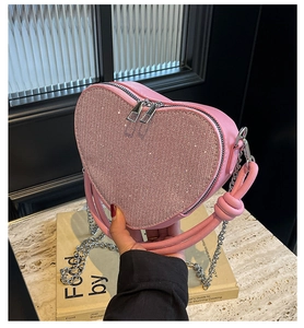 Close-up of pink heart-shaped bag with sparkling sequins and silver metal chain detail