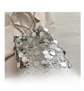 Detail view of large silver sequins and woven chain strap on a fashion bucket bag